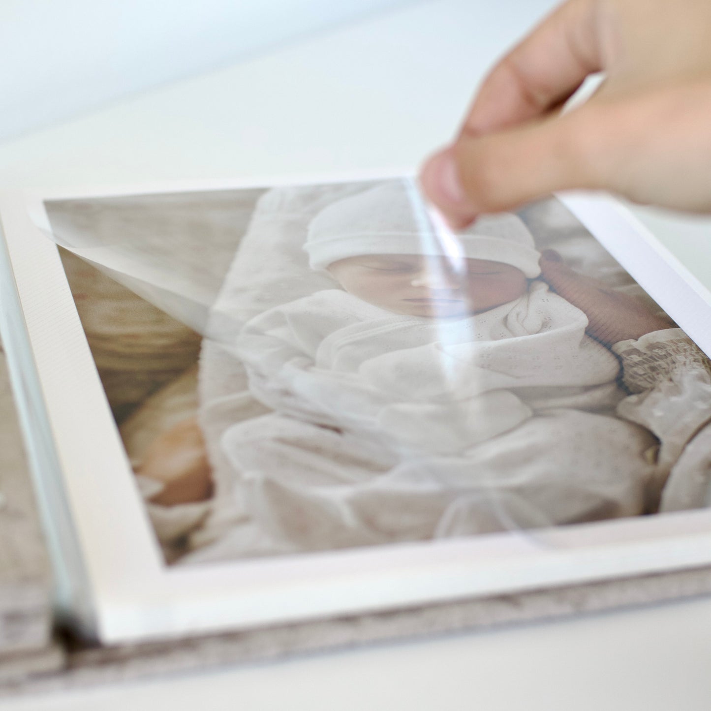 Person cleaning a framed photograph of a baby with a white cloth.