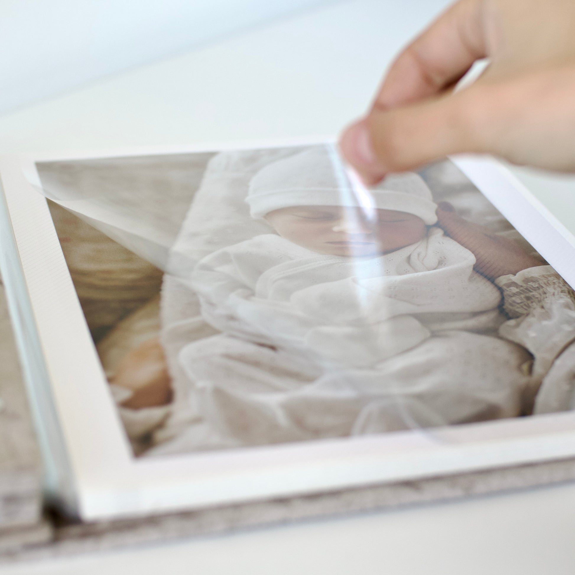 Person cleaning a framed photograph of a baby with a white cloth.