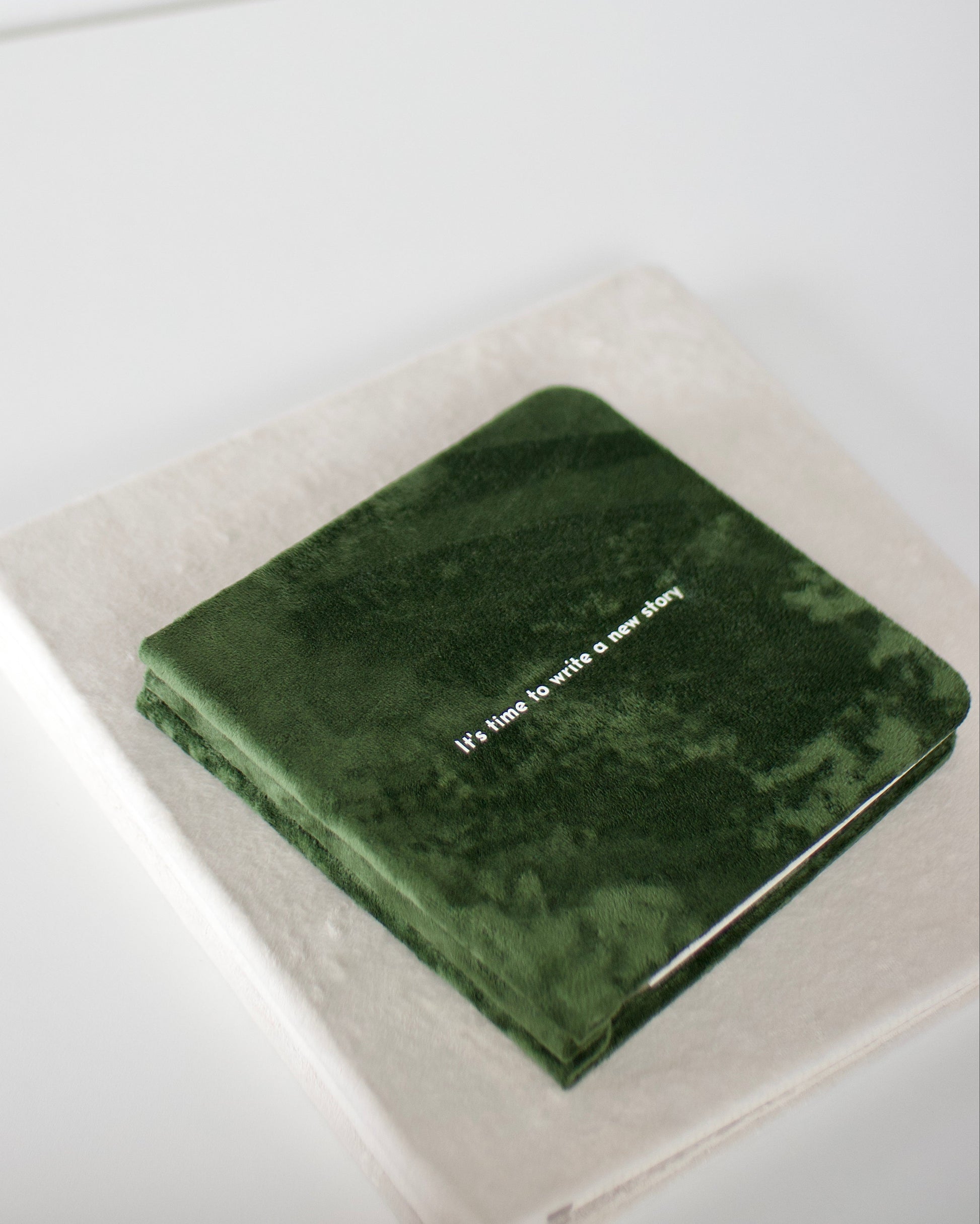 Green notebook with text on a white surface