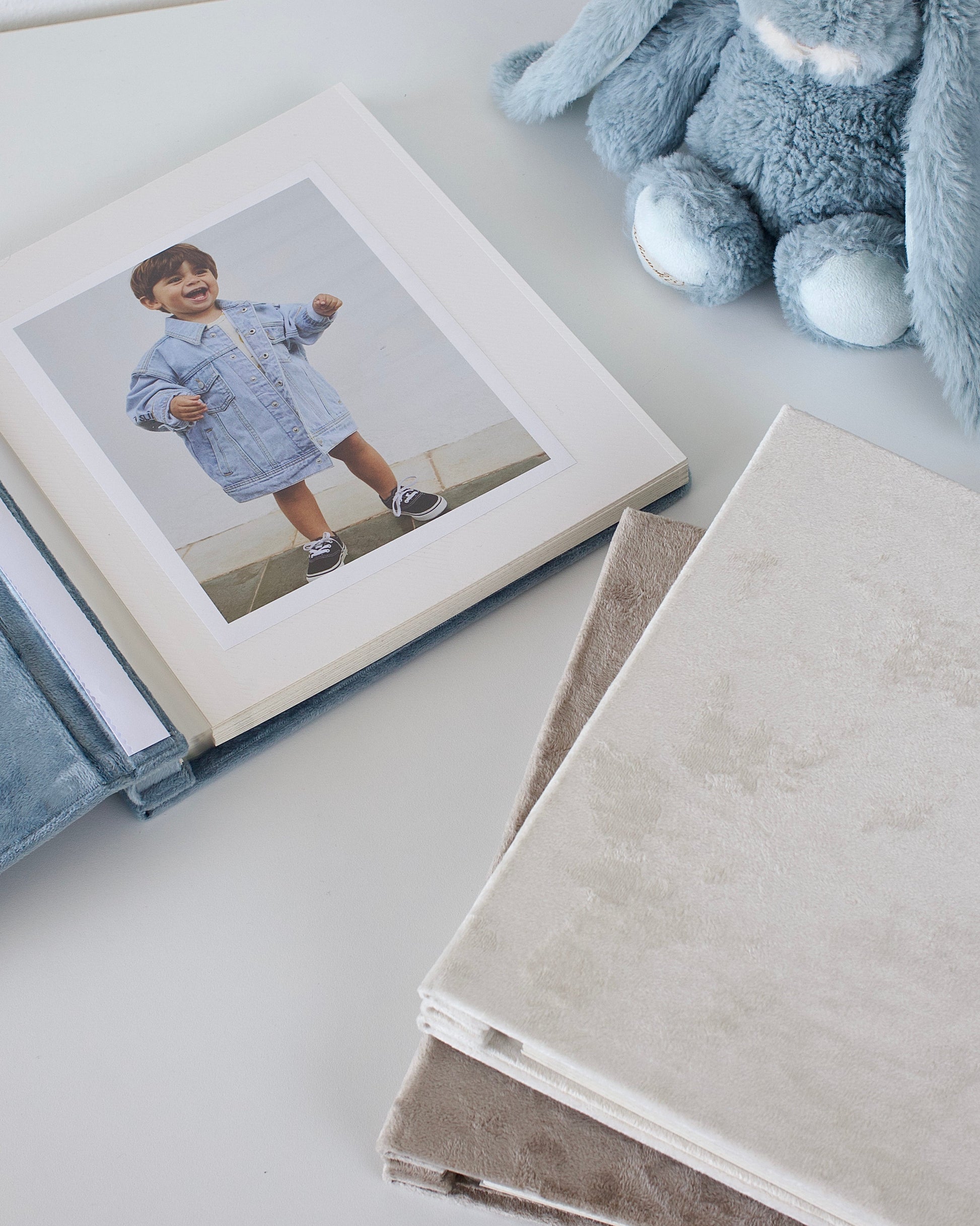 Album with a photo of a child and a plush toy on a light surface
